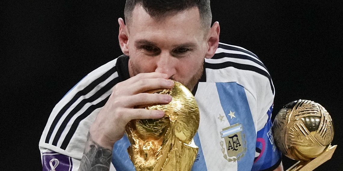 Argentina's Lionel Messi kisses the World Cup trophy with the golden ball trophy in his hand after the World Cup final soccer match between Argentina and France at the Lusail Stadium in Lusail, Qatar, Sunday, Dec. 18, 2022. (AP Photo/Martin Meissner)