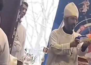بالفيديو تصرف بريء من كاهن يثير الجدل علي الفيس يرش الحضور بماء البركة من خلال مسدس لعبة
